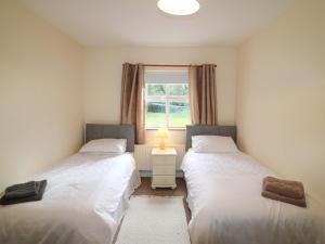 two twin beds in a room with a window at Lugdine Lodge in Glengarriff