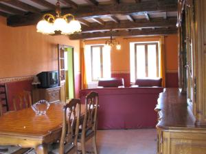 a dining room with a table and a kitchen with windows at Chez clÉmentine in Antheny
