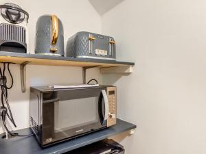 a microwave sitting on a table with two shelves at Forest View Barn in Balcombe