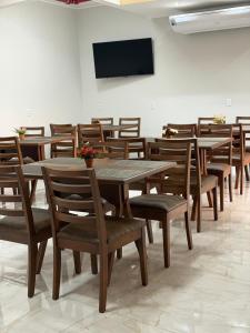a dining room with wooden tables and chairs and a television at Hotel Marinho in Gurupi