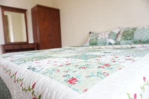 ein Bett mit einer Blumendecke darauf in einem Schlafzimmer in der Unterkunft Warisan Indah Homestay KLIA 1 in Sepang