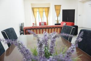 ein Esszimmer mit einem Tisch, Stühlen und lila Blumen in der Unterkunft Warisan Indah Homestay KLIA 1 in Sepang