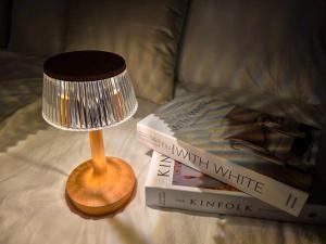 a lamp sitting on a bed with two books at 수원 행궁 Haru Stay in Suwon