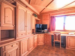 a kitchen with wooden cabinets and a tv and a chair at Chalet Schlitters by Interhome in Schlitters +71 photos