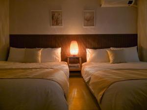 two beds in a room with a lamp between them at 수원 행궁 Haru Stay in Suwon