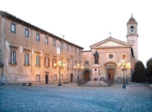 a large building with a clock tower in a courtyard at Piazza Sant'Agostino Rooms in Bagnoregio