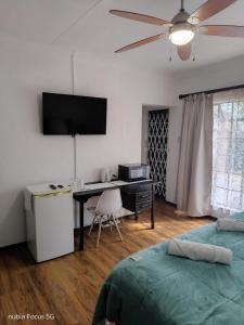 a bedroom with a desk and a television on the wall at Feather Tree Bed and Breakfast in Centurion
