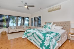 a bedroom with a bed and a couch and windows at Seascape Luxury Beachfront House in Clifton Beach