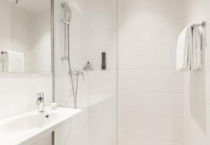 a white bathroom with a shower and a sink at B&B HOTEL Basel in Basel