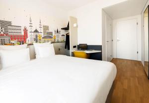 a bedroom with a large white bed with a city view at B&B HOTEL Basel in Basel
