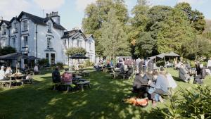 a group of people sitting in the grass in front of a building at Tweedies Bar and Lodge in Grasmere