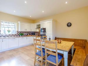 a kitchen with white cabinets and a wooden table and chairs at 3 Bed in Consett oc-29403 in Lanchester