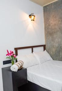 a bedroom with a white bed with a vase of flowers at City Villa Dikwella in Dickwella