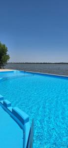 a large swimming pool with blue water and chairs at GyC Laguna Resort in Chascomús