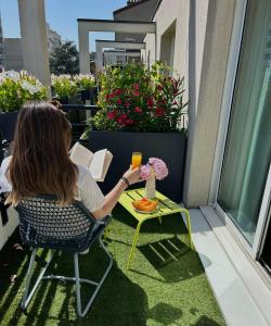 a woman sitting at a table with a book and a drink at Hôbou - ex Hotel Acanthe in Boulogne-Billancourt