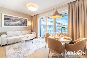 a living room with a table and a couch at Apartamenty BalticON Polanki Aqua in Kołobrzeg