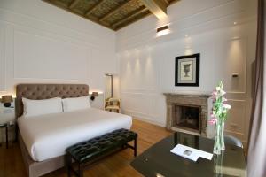 a bedroom with a white bed and a fireplace at Palazzo Goldoni Condotti Collection in Rome +94 photos