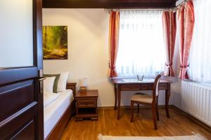 a bedroom with a desk and a bed and a table at Bakonyi Múzsa Vendégház in Bakonyszentlászló