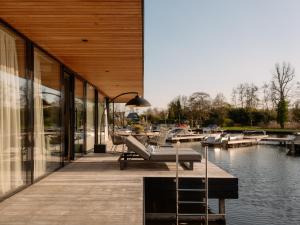 a building with a dock with a bench next to the water at Haven Lake Village in Kortenhoef