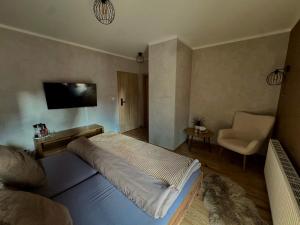 a bedroom with a large bed and a chair at Penzion Bašta in Bílina
