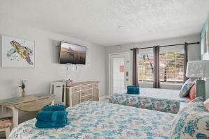 a bedroom with two beds and a desk at Blind Pass Resort Motel in St. Pete Beach