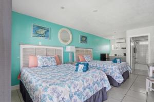 two beds in a room with blue walls at Blind Pass Resort Motel in St. Pete Beach
