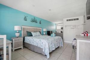 a bedroom with a bed and a blue wall at Blind Pass Resort Motel in St. Pete Beach