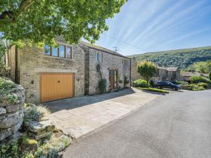 an exterior view of a stone house with a garage at 4 Bed in Skipton oc-89095 in Starbotton