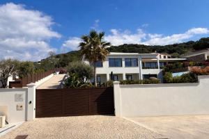 a house with a wooden fence and a palm tree at Domaine LUMISTELLA 2 in Porticcio