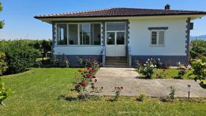 a small white house with flowers in the yard at Vila Rrozhani in Mabë