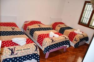 a group of four beds in a room at Vila Rrozhani in Mabë