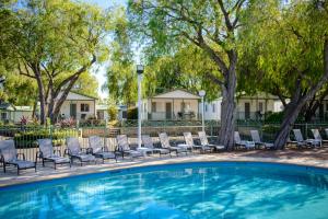 a swimming pool with lounge chairs and trees at Mandalay Holiday Resort and Tourist Park in Busselton