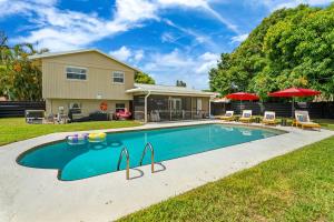 a swimming pool with chairs and umbrellas in front of a house at Your own 5BR Private Oasis! wPrivate PoolPickleball in West Palm Beach
