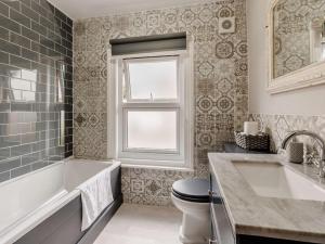 a bathroom with a tub and a toilet and a window at 5 Bed in Pershore oc-91349 in Peopleton +24 photos