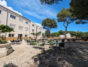 a patio with tables and chairs in front of a building at VTF Village de vacances Le Domaine d'Agde in Agde