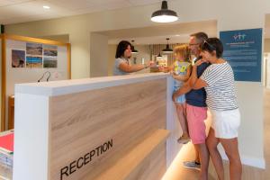 a group of people standing around a reception counter at VTF Village de vacances Le Domaine d'Agde in Agde +31 photos