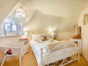 een slaapkamer met een wit bed en een stoel bij 2 Bed in Wareham oc-79305 in East Stoke