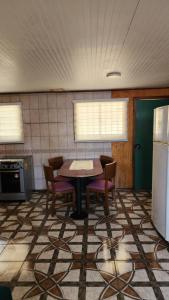 a kitchen with a table and chairs and a refrigerator at Cabaña La Petita in Cherquenco +5 photos