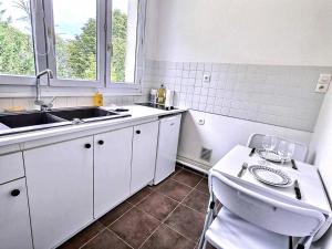 a kitchen with white cabinets and a sink and a table at 5 Mins to Train Station - Free Parking - DisneyLand - Escapade Perchée in Pomponne