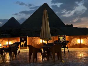 a group of tables and chairs in front of the pyramids at Monument Pyramids View in Cairo