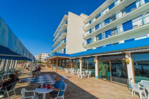 people sitting at tables outside of a building at Hotel Marian Platja in Roses