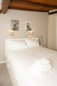 a white bed in a bedroom with two pictures on the wall at Ledy Apartment in Lovere
