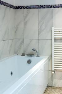 eine Badewanne in einem Badezimmer mit weißen Fliesen in der Unterkunft Plebiscito 10 in Neapel + 47 Fotos