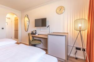 a bedroom with a desk and a clock on the wall at Starzel Rooms in Alling +3 photos