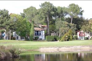 a house on a golf course next to a body of water at Maison villa Lilou, Pierre et vacances, avec piscine, vue sur le golf, plage à 10 min à pied in Moliets-et-Maa