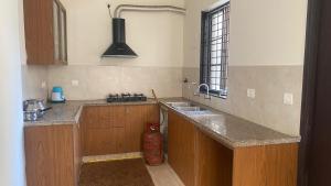 a kitchen with wooden cabinets and a sink and a window at Noble Grand Villa in Mahabalipuram