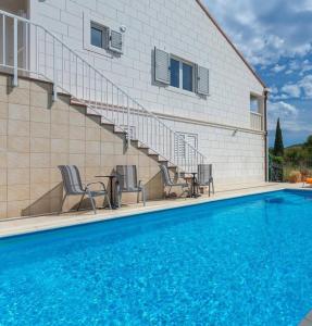 a swimming pool with chairs and stairs next to a building at Villa Florence - Mediterranean GardenPool in Zaton