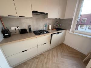 a kitchen with white cabinets and a stove top oven at Apartament Przy Palmiarni in Wałbrzych