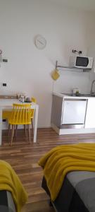 a kitchen with a table and a yellow chair at Cristel malpensa room in Cardano al Campo