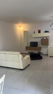 a living room with a white couch and a television at Dimora Maffi in Metaponto